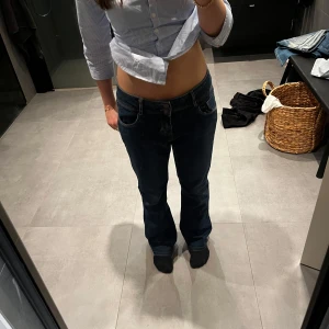 Blåa lågmidjade jeans - Säljer dessa mörkblåa lågmidjade jeansen. De är utsvängda. Midjemåttet är 39cm och innerbenslängden är 100cm. Fint skick