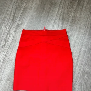 Röd kjol - Snygg röd kjol i en klassisk stil. Perfekt för både vardag och festliga tillfällen. Den har en enkel design utan mönster eller extra detaljer, vilket gör den lätt att matcha med olika toppar och accessoarer.