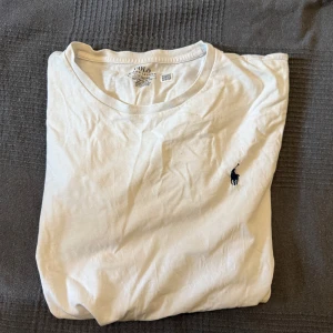 Vit t-shirt från Polo Ralph Lauren - Säljer en klassisk vit t-shirt från Polo Ralph Lauren i storlek L. T-shirten har en broderad logga på bröstet och är i en custom slim fit passform. Perfekt för en stilren look. Ganska välandvänd men har inga defekter eller synliga missfärgningar. Lite liten i storleken så passar även M eller tillockmed S. Tveka inte vid att höra av dig om du har funderingar eller vill ha tydligare bilder.