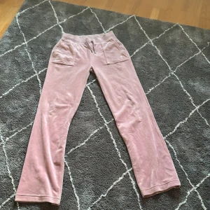 Rosa mjukisbyxor från Juicy Couture - Snygga rosa mjukisbyxor från Juicy Couture i mjukt material. Byxorna har en broderad JC-logga och praktiska fickor fram. Perfekta för en avslappnad stil. Stl S men skulle även kunna passa M. Inte slitna på något sätt.
