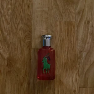Ralph Lauren parfym för kvinnor och män - En elegant parfymflaska från Ralph Lauren i en djärv rosa färg med en grön polo-spelare och en blå siffra 2. Flaskan har en silverfärgad kork och kommer i en matchande förpackning. Den är 50ml aldrig använd pris kan sänkas!