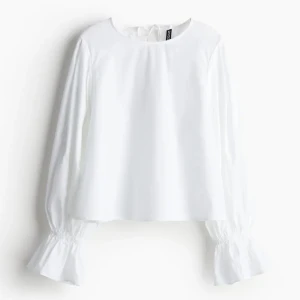 Vit blus med volangärmar - Elegant vit blus med långa ärmar och volangdetaljer vid ärmsluten. Perfekt för en stilren look. Blusen har en rund halsringning och en lös passform.