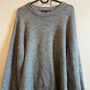 Grå stickad tröja från lager 157 - Mysig grå stickad tröja från lager med rund halsringning. Perfekt för kyliga dagar med sin mjuka och bekväma passform. Ett måste i garderoben för en stilren look.