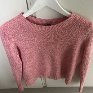 Rosa stickad tröja från Divided - Säljer en söt rosa stickad tröja från Divided. Tröjan har en melerad design med långa ärmar och en rund halsringning. Perfekt för kyligare dagar och ger en mysig känsla. Passar bra till jeans eller kjol för en avslappnad look.