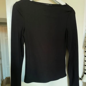 Svart långärmad topp från Bik Bok - Basic topp från BikBok med slits på armarna och lätt boatneck Stummare topp och väldigt mjuk, tyvärr kommer den dock inte tillräckligt till användning 