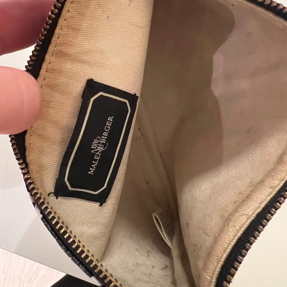 Snygg kuvertväska från Malene Birger i svartvitt mönster. Väskan har en praktisk dragkedja och ett stilrent mönster som ger en elegant touch. Perfekt för att bära med sig det nödvändigaste.. Laukut & Käsilaukut.