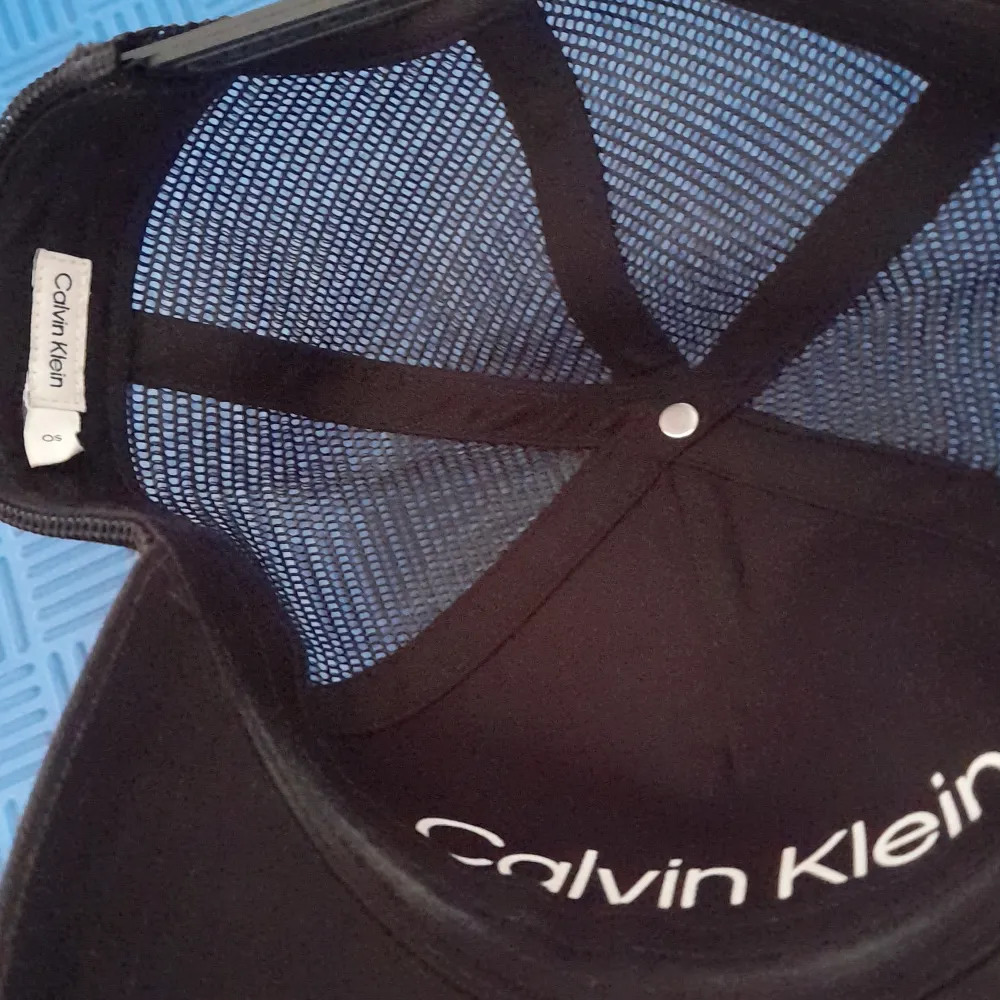 Snygg svart keps från Calvin Klein med broderad logga framtill. Kepsen har ett nätmaterial på baksidan för bättre ventilation och justerbart spänne för perfekt passform.. Asusteet.