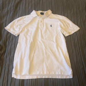Vit pikétröja från Ralph Lauren - Säljer en klassisk vit pikétröja från Ralph Lauren i storlek M. Tröjan har korta ärmar och en broderad logotyp på bröstet. Perfekt för en stilren och avslappnad look.