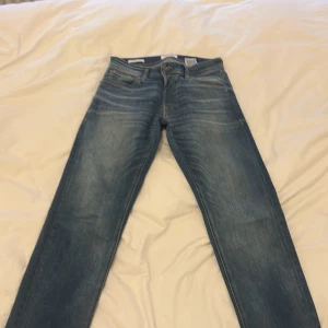 Blå jeans från Jack & Jones - Snygga blå jeans från Jack & Jones med en klassisk femficksdesign. De har en bekväm passform och är perfekta för en avslappnad stil. Jeansen har en knappgylf och är tillverkade i slitstarkt denim.