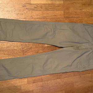 Beige chinos från Paul & friends - Snygga beige chinos från Paul & friends i 100% bomull. De har en klassisk design med knappstängning och raka ben. Perfekta för en stilren look.