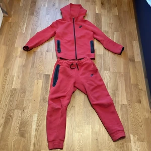 Röd Nike tech tracksuit - Säljer en röd Nike tech i storleken XL barn eftersom den inte kommer till användning. Jag säljer hela tracksuiten för 750 kr men om man vill ha tröjan eller byxorna separat kan vi diskutera priset. Listpris för byxorna:879 kr. Och listpris för tröjan: 999 kr. Kontakta vid minsta fundering. 
