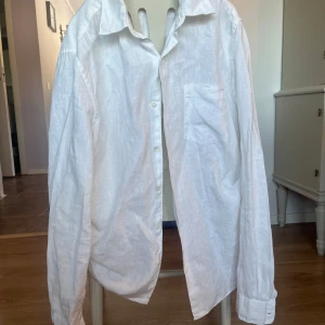 Vit linneskjorta från A Day's March - Säljer en stilren vit skjorta i linne från A Day's March. Skjortan har en klassisk krage och knappar framtill. Perfekt för en avslappnad men ändå elegant look. Passar bra till både jeans och chinos.