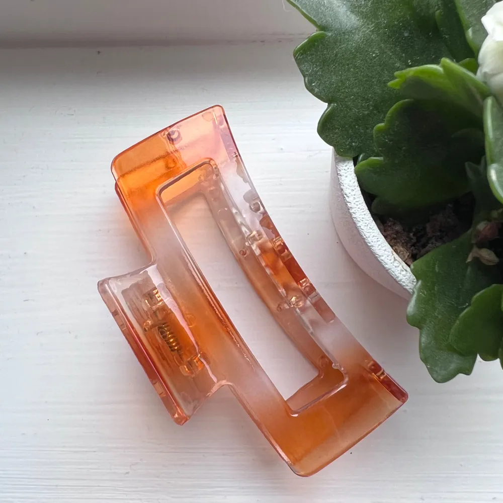 Snygg och stilren hårklämma i transparent orange plast. Perfekt för att hålla håret på plats med en modern touch. Klämman har en rektangulär form och är lätt att använda. Använd en handfull gånger 🧡 Storlek: 9cm lång. Asusteet.