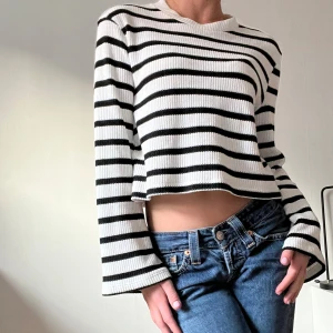 Randig stickad tröja - Snygg randig tröja i svart och vit. Tröjan är croppad och har långa breda ärmar.