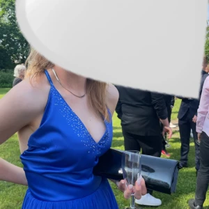 Blå balklänning med öppen rygg - Elegant blå långklänning med öppen rygg och smala axelband. Klänningen har en v-ringad framsida och ett flödande kjolparti som ger en vacker siluett. Perfekt för speciella tillfällen. Andvänd en gång men i mycket fint sick. Den är special sydd efter mina mått och önskemål så väldigt unik.