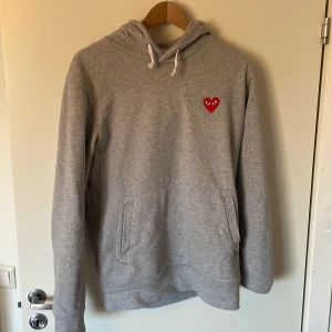 Grå hoodie från Comme des Garçons - Säljer en stilren grå hoodie från Comme des Garçons. Tröjan har en bra passform. Aningen liten i storleken. Så passar L också. Enda defekten är smärta som är lite konstiga 