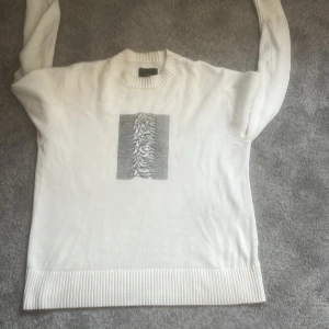 Neuw x Joy Division - Säljer en vit tröja från Joy Division x Neuw med det ikoniska 'Unknown Pleasures'-trycket på baksidan. Tröjan har långa ärmar och en ribbad kant vid ärmslut. Nypris 2600kr. Oz S men som L