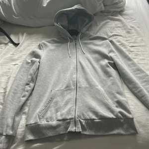 Grå hoodie från 157 - Säljer en stilren grå hoodie från 157 i storlek S. Den har en dragkedja framtill och praktiska fickor. Perfekt för en avslappnad look med sin mjuka och bekväma passform.