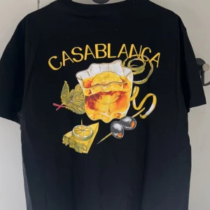 Svart t-shirt från Casablanca - Snygg svart t-shirt från Casablanca med ett coolt drinkmotiv på både fram- och baksidan. Perfekt för en avslappnad stil med en touch av elegans. 