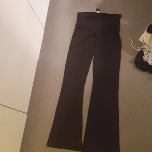 Svarta byxor från Gina Tricot - Snygga svarta yoga pants från Gina Tricot i storlek XS. Byxorna har en bootcut-stil och är högmidjade, vilket ger en trendig look. Perfekta för att matcha med olika toppar och accessoarer.