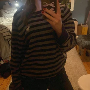 Randig tröja från Abercrombie & Fitch - Säljer en randig tröja från Abercrombie & Fitch i svart och grått. Tröjan har ett broderat älgmärke på bröstet och är långärmad. Perfekt för en avslappnad stil. har ett litet hål nedanför älgen på bröstet men det syns inte jätteväl