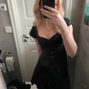 Svart vintage klänning med knappar  - Kort svart klänning med knappar och fickor framtill och korta ärmar. Mycket fin passform 😍! 