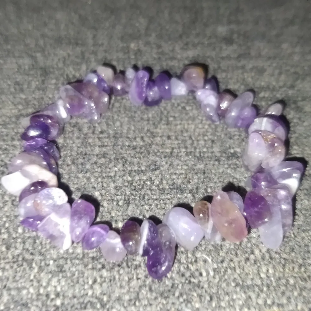 Säljer två elastiska armband med naturliga stenar. Det första armbandet har bruna och gyllene stenar, medan det andra har lila och ljusa stenar. Dessutom ingår en polerad sten i svart och vit nyans, perfekt som dekoration eller samlarobjekt.. Asusteet.