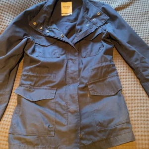 Mörkblå fieldjacka från Dobber - Säljer en stilren mörkblå fieldjacka. Jackan har flera praktiska fickor framtill. Den är utrustad med både dragkedja och knappar för stängning. Perfekt för höst och vår. Skick 8.5/10 samt perfekt för en casual look. Passar xs-s.