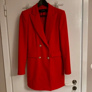 Röd kavaj från Zara - Snygg röd kavaj från Zara med dubbelknäppning och guldknappar. Den har en klassisk krage och långa ärmar, perfekt för att ge en färgklick till din outfit. Passar bra till både formella och avslappnade tillfällen. Köpt för 1200 och den är i fint skick, säljer även matchande kostymbyxor till👏🏼👏🏼