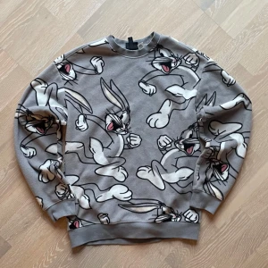 Grå sweatshirt med tryck från H&M - Säljer denna riktigt gosiga grå sweatshirten från H&M. Den har snurre sprätt över hela sig. Perfekt för Kaninälskaren som också gillar mysiga stunder i sköna kläder🐰. Det står att tröjan är XS men den passar även mig som har M