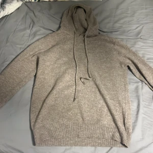 Beige Kashmir/merionoul Hoddie  - Mysig beige hoodie med långa ärmar och justerbar huva. Perfekt för våren och avslappnade stunder. Ribbstickade muddar vid ärmslut och nederkant ger en skön passform. Bra pris nypris köpt för 1500 kan gå ner i pris passar både stor s och m aldrig använd.