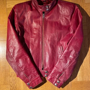 Vintage röd läderjacka - Snygg röd skinnjacka i storlek XS med dragkedja och knappar vid kragen och nedtill!⭐️ Den är i använt skick och dragkedja är trasig nedtill, går fortfarande att stänga men kan gå upp! Kan skicka fler bilder vid intresse 🫶🏼Äkta läder 