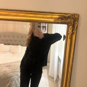 Svart ribbad blus  - Snygg svart ribbad blus/topp med långärmad design. Perfekt för en stilren look. Toppen har en elegant passform som framhäver figuren. Den är plisserad som man ser på bild 2