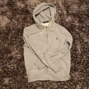 Grå hoodie från Ralph Lauren - Säljer en stilren grå hoodie från Ralph Lauren med dragkedja och huva. . Perfekt för en avslappnad look. Skick 8/10 inga skador använd några gången pris 650 kan diskuteras vid snabb affär storlek S
