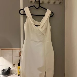 Vit klänning från Gina Tricot - Elegant vit klänning från Gina Tricot med en stilren design. Klänningen har en axelbandslös stil och en liten slits framtill som ger en sofistikerad touch. Perfekt för speciella tillfällen. Hade den själv på studenten.