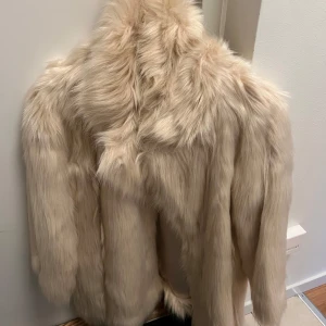 Oanvänd benvit - vit  fuskpäls jacka  - Helt oanvänd, lappen kvar, fuskpäls jacka i benvitt som inköptes på Chiquelle för ett par år sedan för 1000kr men som bara har hängt i garderoben. I nyskick med andra ord!  I storlek large men är mer som en medium skulle jag säga. Superfin och fluffig med glansig insida. Kortare i ärmarna.  Hämtas i Blackeberg eller postas.  Katt finns i hemmet. 