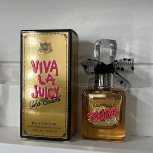 Viva La Juicy Gold Couture Eau de Parfum - Elegant och lyxig parfym från Juicy Couture i en gyllene flaska med en dekorativ svart rosett. Doften är en del av Viva La Juicy-serien och kommer i en 30 ml flaska. Förpackningen är guld med rosa text, vilket ger en glamorös känsla.testad en gång så i princip helt full 