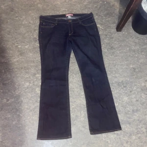 Mörkblå jeans low waisted  - Snygga mörkblå jeans med klassisk ficksdesign och kontrastsömmar. Jeansen har en bootcut passform men inte så drastisk bootcut .De har en knappgylf och är tillverkade i ett slitstarkt denimtyg. Waist 34 Length 32