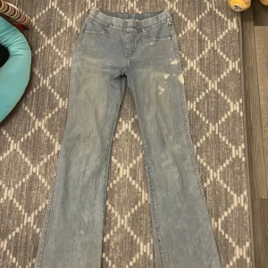 Ljusblå jeansbyxor från H&M - Säljer ett par ljusblå jeansbyxor från H&M. Byxorna har en klassisk femficksdesign och en bootcut-stil. Perfekta för en avslappnad look. Har dock inte jeans material mer som jeans tights men väldigt sköna!