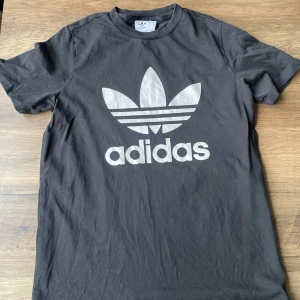 Svart t-shirt från Adidas - Säljer en svart t-shirt från Adidas med det klassiska trefoil-logotypen tryckt i vitt på framsidan. 