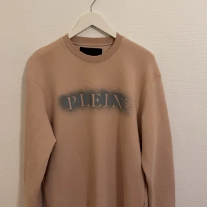 Philipp Plein tröja - Säljer en stilren beige sweatshirt från Philipp Plein med tryck framtill. Tröjan har långa ärmar och är tillverkad i en mjuk bomullsblandning. Perfekt för en avslappnad look.