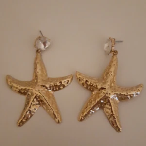 Guldiga sjöstjärneformade örhängen - Snygga örhängen i form av sjöstjärnor i guld. Original pris är 200