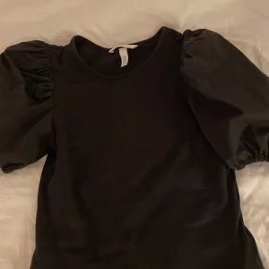 Svart topp med puffärmar från H&M - Säljer en svart topp från H&M med puffiga kortärmar i storlek xs. 