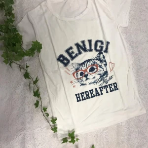 Tjejer t-shirt  - Säljer tjej t-shirt med tryck. Den första har en katt med glasögon och texten 'BENIGI HEREAFTER'. Den andra har en glad smiley och texten 'CHEARSHAT EARSHATE'. Den tredje har ett stort 'A' och texten 'POREVER'. Perfekt för en avslappnad stil!   Helt ny.     69kr/st . 55% bomull. 45% spandex, bra på stretch 