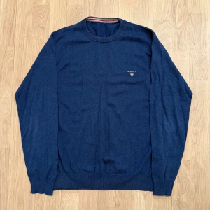 Mörkblå tröja från Gant - Snygg mörkblå tröja från Gant med rund halsringning och diskret logga på bröstet. Tröjan har långa ärmar och ribbade muddar vid ärmslut och nederkant. Perfekt för en stilren look. Pris kan diskuteras.