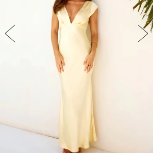 Ljusgul långklänning med öppen rygg - Elegant ljusgul långklänning som är slutsåld överallt!!! Prislappen sitter kvar. Satin med v-ringad hals och öppen rygg. Perfekt för sommarens festligheter. Klänningen har en smickrande passform och korta ärmar. KOM MED ETT BUD VID INTRESSE 