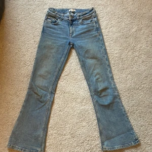 Blå bootcut jeans - Snygga blå bootcut jeans med klassisk femficksdesign och dragkedja. Perfekta för en avslappnad stil med en touch av retro. Passar bra till sneakers eller boots.