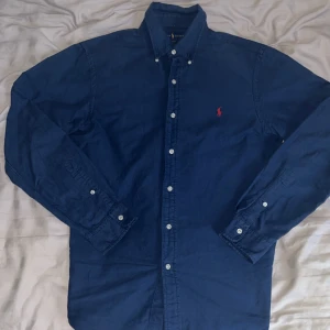 Blå skjorta från Ralph Lauren - Säljer en snygg, rätt ny blå Ralph lauren Oxford skjorta. Den är i storlek Medium. Köpte den ungefär för ett halvår sedan och använt den 3 gånger. Den är väldigt skön och perfekt för sommardagar men också för speciella tillfällen. Nypris: 1395kr Mitt pris: 399kr. Överväg inte att ställa frågar om fler bilder och annat