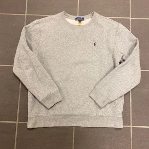 Grå sweatshirt från Polo Ralph Lauren - Säljer en stilren grå sweatshirt från Polo Ralph Lauren. Köpt från kids brandstore och är i storlek 18-20 men passar som S. Mycket fint skick. Priset är ej hugget i sten.