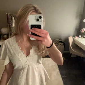 Vit blus med spetsdetaljer - Säljer en söt vit blus med v-ringning och spetsdetaljer. Blusen har korta ärmar och ett fint broderat mönster. Perfekt för en somrig look!🌸🌸